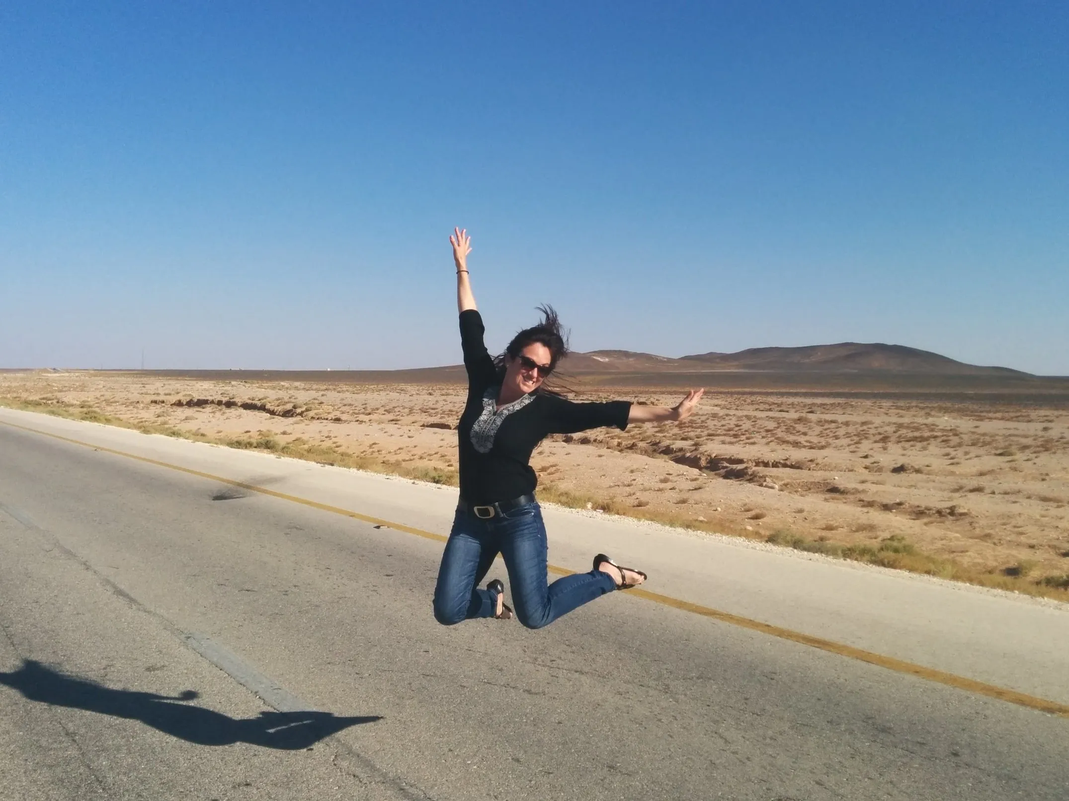Natasha jumping joyfully in a desert landscape